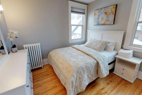 1 dormitorio blanco con 1 cama y 2 ventanas en Bright, Clean, Private. In the Heart of Downtown! Parking, Wi-Fi and Netflix included en Ottawa