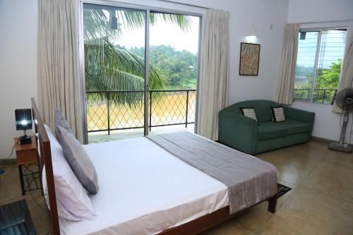 a bedroom with a bed and a chair and a large window at Riverside Suites in Kandy
