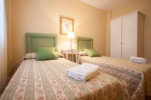 1 dormitorio con 2 camas con cojines verdes en Macarena Flat en Sevilla