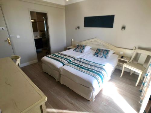 a bedroom with a large bed and a chair at Hôtel Méditerranée in Le Lavandou