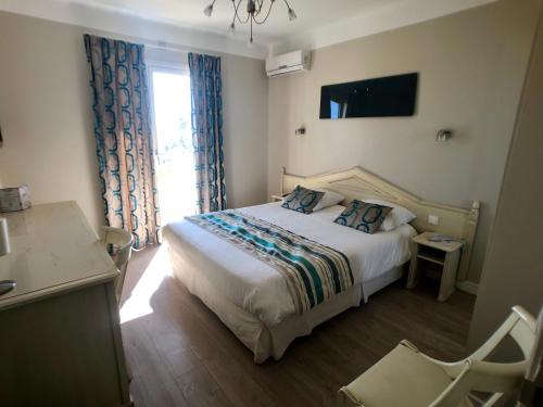 a hotel room with a bed and a window at Hôtel Méditerranée in Le Lavandou