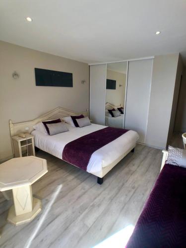 a large bedroom with a large bed and wooden floors at Hôtel Méditerranée in Le Lavandou