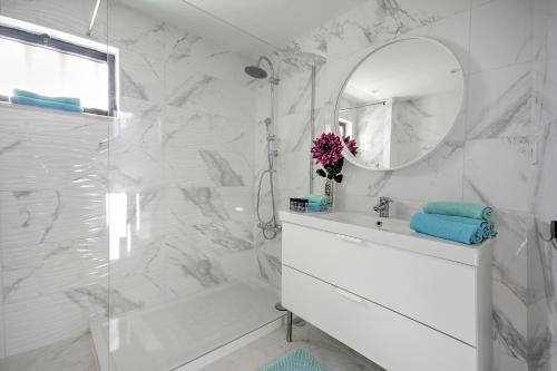 um banheiro branco com uma pia e um espelho em In Faro with Sea View em Faro