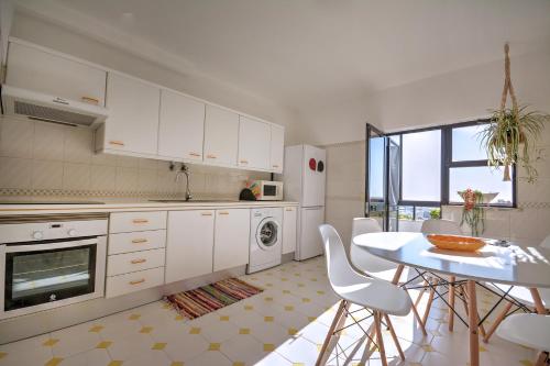 a kitchen with white cabinets and a table with chairs at In Faro with Sea View in Faro