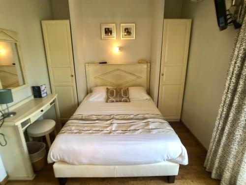 un pequeño dormitorio con una cama con un bolso en Hôtel Méditerranée, en Le Lavandou