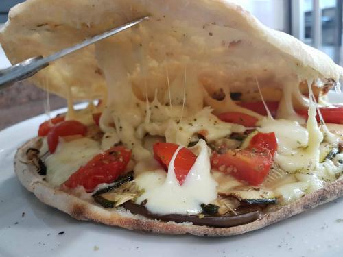 a pizza with cheese and vegetables on a plate at Hotel Kroma in Ragusa