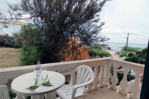 a white table and chairs on a balcony with the ocean at House Dimitri Agios Georgios Pagoi Corfu in Agios Georgios Pagon