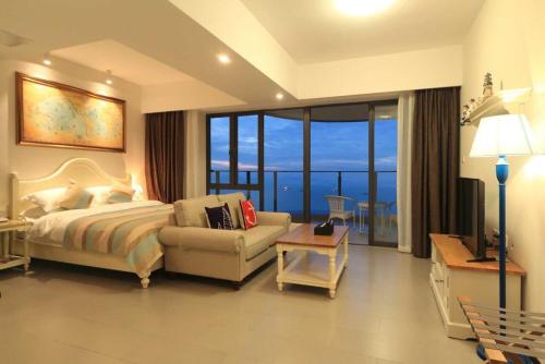 a bedroom with a bed and a couch and a television at 惠东巽寮湾无敌海景公寓 in Huidong