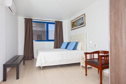 プラヤ・ブランカにあるVilla Beyond Playa Blancaのベッドルーム1室(ベッド1台、椅子、窓付)