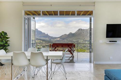 a dining room with a table and chairs and a large window at Mount Bay in Hout Bay