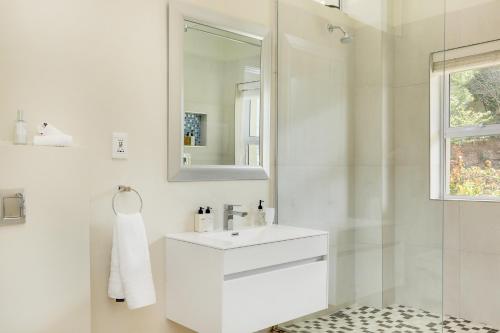 a white bathroom with a sink and a mirror at Mount Bay in Hout Bay