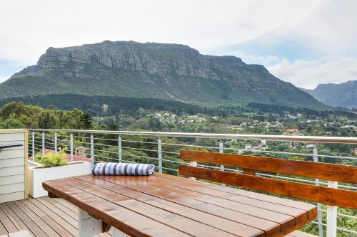 a wooden bench sitting on a balcony with a mountain at Mount Bay in Hout Bay