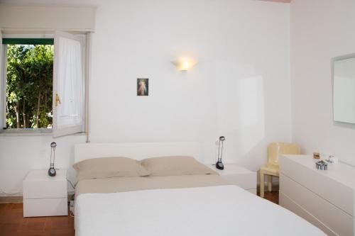 Un dormitorio blanco con una cama y una ventana. en Villa Iaia, en Fontane Bianche