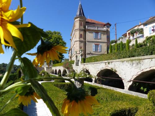 a building with a tower and a bridge and yellow flowers at Cottage du Château "Les Sources d'Arvory" in Valensole