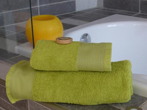 a green towel sitting on top of a bath tub at Cottage du Château "Les Sources d'Arvory" in Valensole