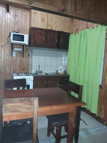 a kitchen with a wooden table and a green curtain at Cabañas Los Timbó in Ituzaingó
