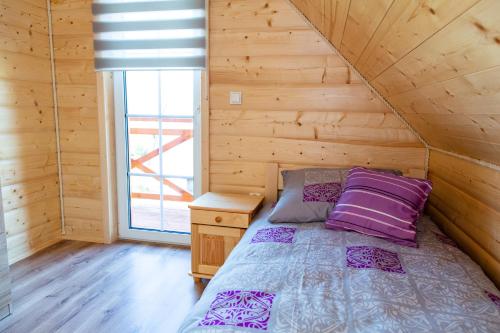 a bed with purple pillows in a wooden room at Domki na Beskidzie 1861 in Istebna