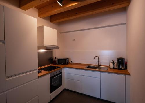 uma pequena cozinha com armários brancos e um lavatório em Ferienloft in der blauen Scheune em Binzen