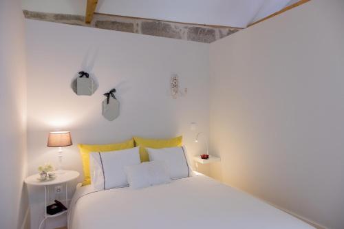 Dormitorio blanco con cama blanca y almohadas amarillas en Sunday - Alda's Vintage Apartments with Free Parking en Oporto