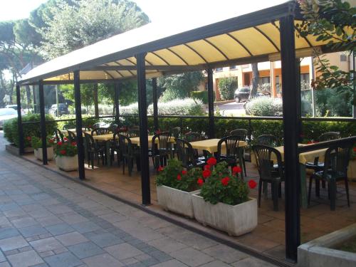 un patio coperto con tavoli, sedie e fiori di Hotel Cucciolo a Donoratico