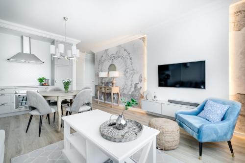 a white living room with a tv and a table at Apartamenty Tespis - Francuska Atal Park in Katowice