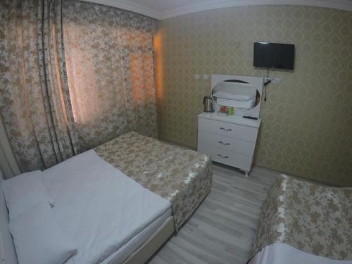 a bedroom with two beds and a dresser and a tv at Pınar Vintage House in Pamukkale
