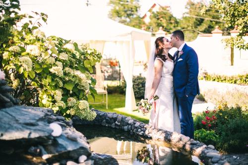 a bride and groom kissing in front of a pond at Villa Oselya in Kyiv