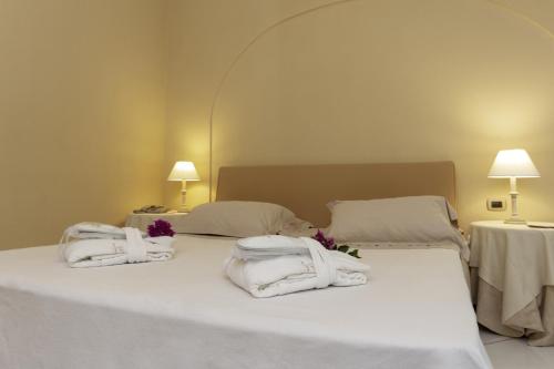 a hotel room with a bed, table and lamps at Hotel Simius Playa in Villasimius