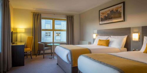 a hotel room with two beds and a table at Maldron Hotel & Leisure Centre Limerick in Limerick