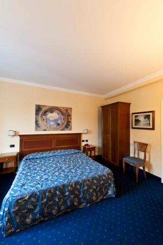 a hotel room with a bed and a chair at Albergo Costantini in Tarcento