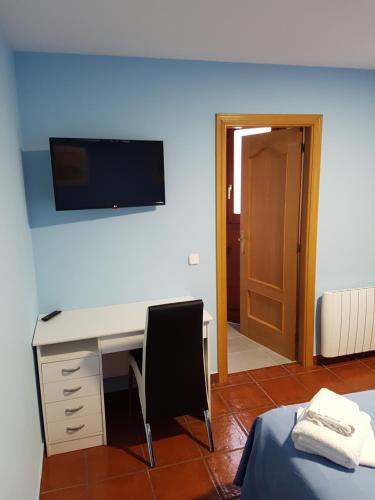 1 dormitorio con escritorio, silla y TV en la pared en HOSTAL ITXASO-ENEA, en Aoiz