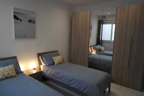 - une petite chambre avec 2 lits et un miroir dans l'établissement Marsaskala Penthouse Apartment, à Marsaskala