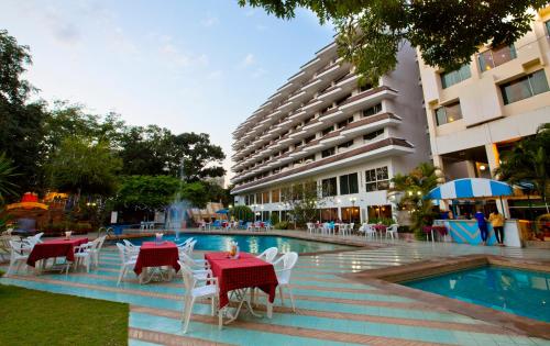 a hotel with tables and chairs next to a swimming pool at Charoen Hotel in Udon Thani