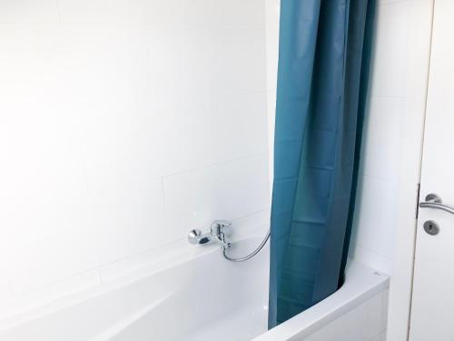 Baño con cortina de ducha azul junto a la bañera en Beautiful Modern Apartment, en Bruselas