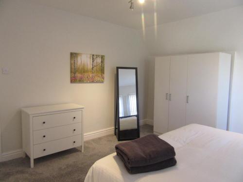 a bedroom with a bed and a dresser and a mirror at No 6 AT 19 IVANHOE - LARGE 2 BED NEAR SEFTON PARK AND LARK LANE in Liverpool