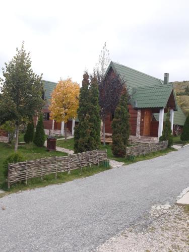 a house with a wooden fence next to a street at Holiday Home Vile Calimero in Žabljak