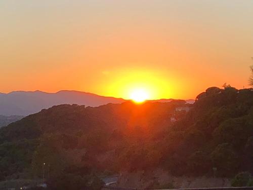 a sunset in the mountains with the sun setting at Luxury Villa Marina in Lloret de Mar