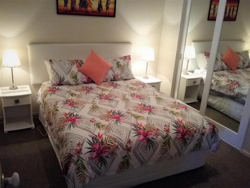 a bedroom with a bed and two lamps and a mirror at Paradise Views Luxury 2BR Apartment in Paihia