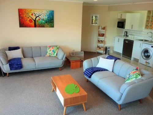 a living room with two couches and a table at Paradise Views Luxury 2BR Apartment in Paihia