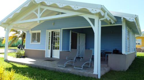 a blue house with chairs on a porch at La Ferme des Etangs in Rivière-Salée