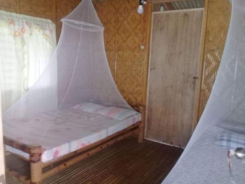 a small bedroom with a bed with a net on it at Junior & Nemesia's Cottages in Baclayon