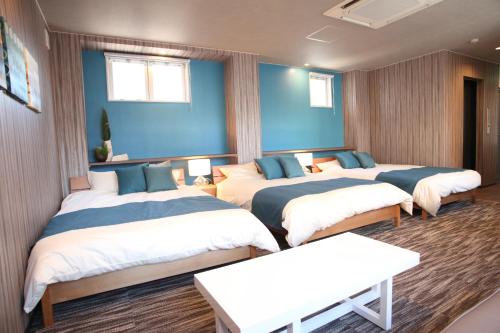 3 łóżka w pokoju z niebieskimi ścianami w obiekcie Tanimachi 4chome 5F w Osace