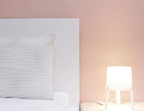 a bed with a white pillow and a lamp at TheDaun Homestay Seri Iskandar, Perak in Seri Iskandar