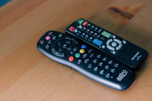 two remote controls sitting on top of a table at TheDaun Homestay Seri Iskandar, Perak in Seri Iskandar