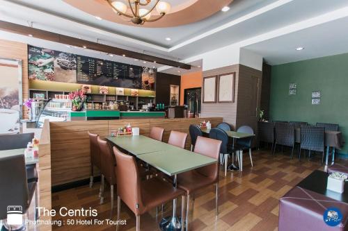 a restaurant with a table and chairs and a counter at The Centris Hotel Phatthalung in Phatthalung