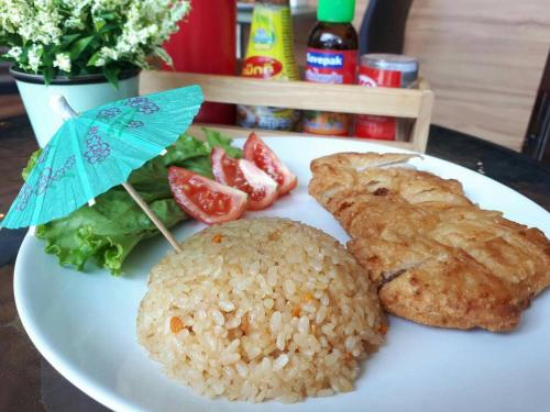 a plate of food with rice and vegetables and an umbrella at The Centris Hotel Phatthalung in Phatthalung