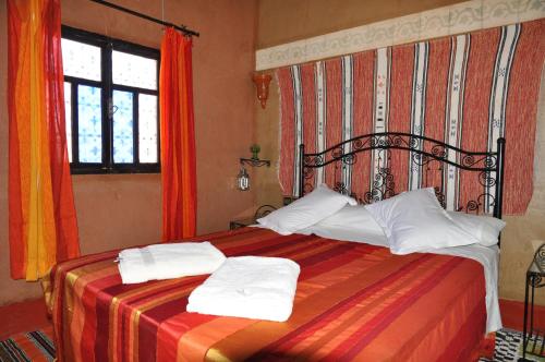 a bedroom with a bed with two towels on it at Kasbah Ait BenHadda in Skoura