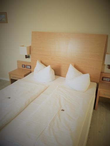 a large white bed with two pillows on it at Pension Am Pollingpark in Dessau
