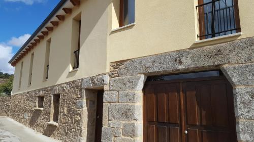 a stone building with a wooden garage door at O Trancallo in Viana do Bolo