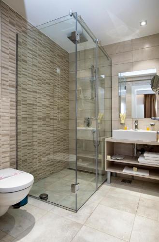 a bathroom with a shower and a toilet and a sink at Hotel Fobra in Podgorica